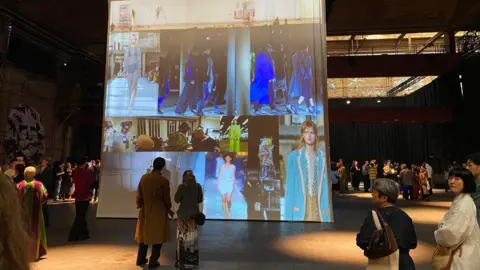 Georgia Bell Images of Dries Van Noten's runways are displayed on a huge block in the centre of the room at the pre-show cocktail party