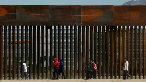 Reuters Migrants walk along the border fence after crossing illegally into El Paso, Texas