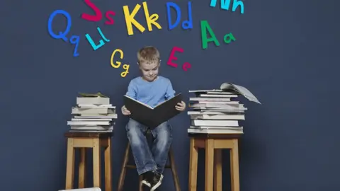 Getty Images A boy surrounded by books reading