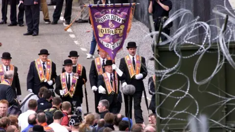 Pacemaker PACEMAKER BELFAST 4/7/99 Orangemen and supporters surver the mass of razor wire in the fields surrounding Drumcree church preventing them from marching down the Garvaghy road on Sunday afternoon.