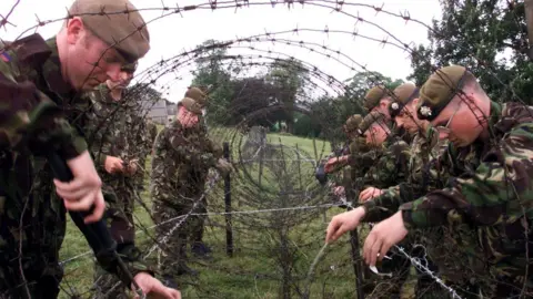 Pacemaker PACEMAKER BELFAST 2/7/99 British soldiers errect rows of razor wire in the fields surrounding Drumcree church in preparation for Sundays banned Orange parade.