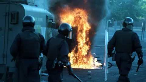 Pacemaker PACEMAKER BELFAST 06/07/98 RUC riot squad officers move i n to quell rioting in the Sandy Row area of South Belfast this evening. The second night of rioting after the Drumcree stand off.