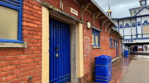 BBC/George Carden A set of public toilets in Eastbourne, locked up but painted in the district's colours of blue and gold.