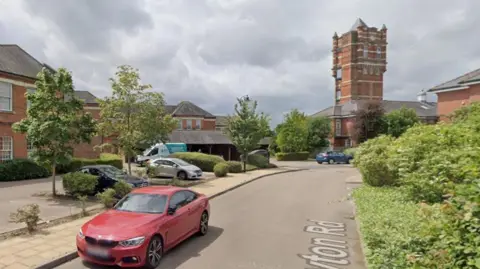 Google A Google image of Netherne-on-the-Hill village, with a red car on a road in the foreground and red brick buildings in the background