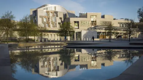 PA Media The Scottish Parliament building in Edinburgh, reflected in a pool