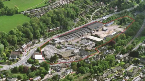 Stroud District Council An aerial view of the Brimscombe Port site, an industrial area with large warehouses surrounded by homes and green countryside