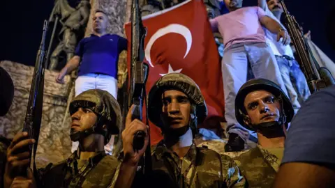 Getty Images Turkish solders stand with guns at Taksim square as people react in Istanbul on July 16, 2016.