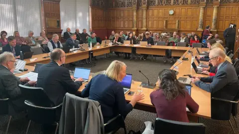 George Torr/BBC Members of Derbyshire County Council round the cabinet table and members of the public to the end of the packed room.