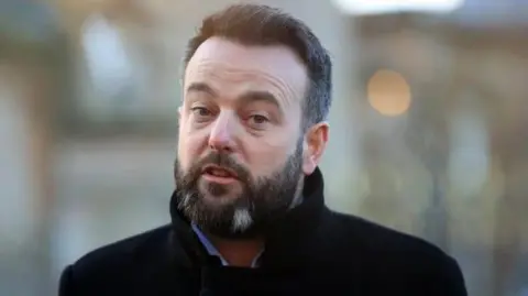 PA Media Colum Eastwood in a black overcoat and blue shirt