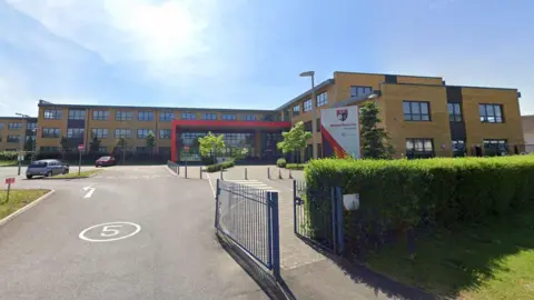 Google Winterbourne Academy in South Gloucestershire. It is a brown brick building with a red porch.