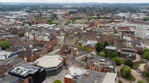 Getty Images An aerial view over the city of Wolverhampton on an overcast day. There are old factory buildings and new developments, with hills in the background.