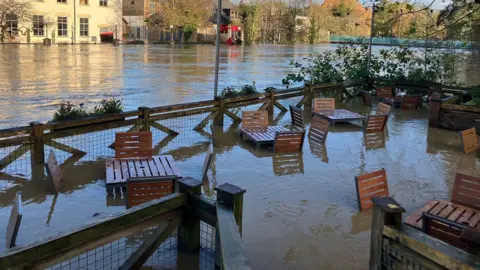 BBC Tables and chairs outside a restaurant submerged in flood water