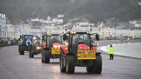 Getty Images Tractors on the promenade at Llandudno with a sign Labour War on Countryside
