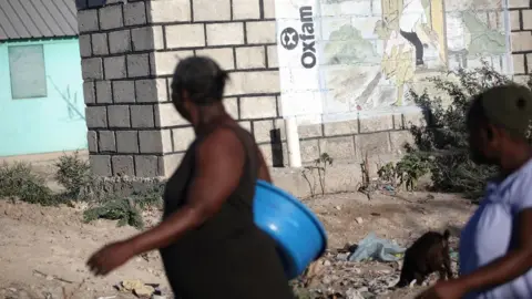 Oxfam Women walking past Oxfam mural in Haiti in 2018
