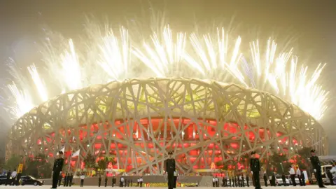 Getty Images Fireworks light up the sky as paramilitary policemen stand guard outside the National Stadium during the Opening Ceremony for the Beijing 2008 Olympic Games