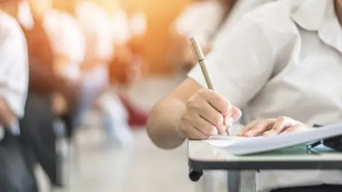 Getty Images Student completing exam at desk
