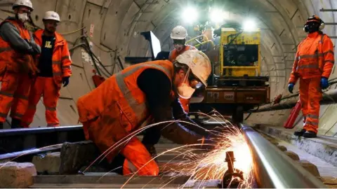 Getty Images Construction workers work on a section of train track inside a Crossrail tunnel, beneath Stepney in east London in 2016
