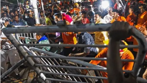 AFP This photo taken on May 14, 2019 shows supporters of the Bharatiya Janata Party (BJP) facing off with Indian police next to torn down barricades during clashes between rival groups during a campaign rally event held by BJP president Amit Shah in Kolkata