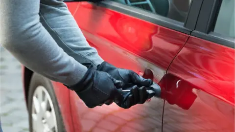 Getty Images stock image of person breaking in to a car