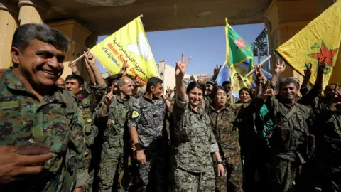 Reuters Syrian Democratic Forces fighters celebrate victory against IS militants in Raqqa, Syria, on 17 October 2017