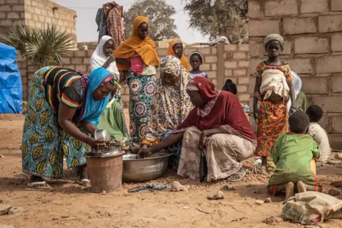 Olympia de Maismont / AFP Women and children stand outside accommodation made available by the community for Internally Displaced People (IDP) from northern Burkina Faso in Kaya, on 22 January 2019.