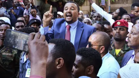 Getty Images Jawar Mohammed (C), a member of the Oromo ethnic group who has been a public critic of Abiy, addresses supporters that had gathered outside his home in the Ethiopian capital, Addis Ababa after he accused security forces of trying to orchestrate an attack against him October 24, 2019
