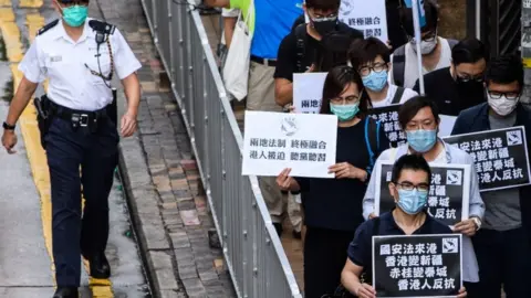 Getty Images Pro-democracy protesters hold black placards as they march on the Chinese Liaison Office in Hong Kong