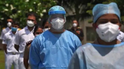 AFP The staff of INHS Asvini hospital wearing protective gear stand before they were showered with flower petals by Indian Navy"s Chetak helicopter as part of an event to show gratitude towards the frontline warriors fighting the coronavirus disease (COVID-19) outbreak, in Mumbai