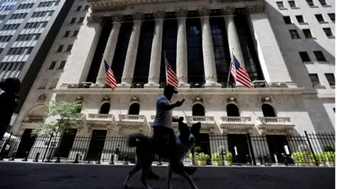 Reuters A man walks a dog in the shade away from the midday sun past the New York Stock Exchange (NYSE) building in Manhattan, during hot weather in New York City, New York, U.S., August 11, 2020