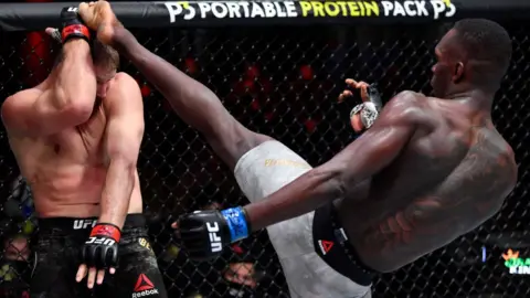 Getty Images Israel Adesanya of Nigeria (R) kicks Jan Blachowicz (L) of Poland in their UFC light heavyweight championship fight during the UFC 259 event at UFC APEX in Las Vegas, Nevada - Saturday 6 March 2021