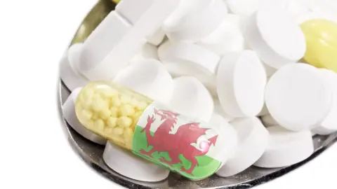 eyegelb/getty The national flag of Wales on a capsule and pills on a spoon