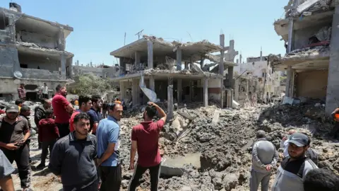 Reuters A group of men standing by bombed out buildings in Gaza