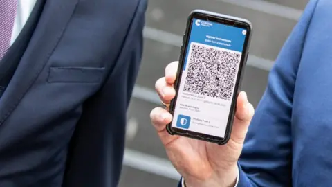 EPA A man hols a mobile phone displaying an EU Digital Covid Certificate