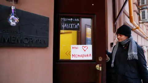 Reuters A man enters an office of the human rights group Memorial in Moscow, Russia December 29, 2021. Placards read: "Memorial forever" (top) and "We love Memorial"