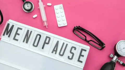 Getty Images Menopause sign with glasses and a blood pressure gage on a pink background