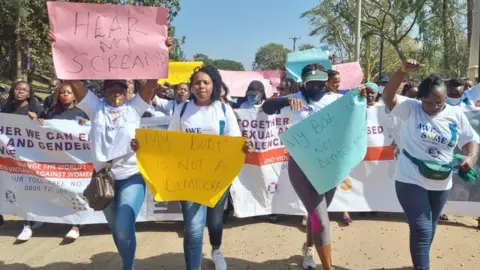 Rally of women Kenya hold colourful signs which reads, 'hear my scream'.