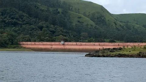 Getty Images File photo showing Mullaiperiyar Dam stretching from the lake to a luscious hillside with trees