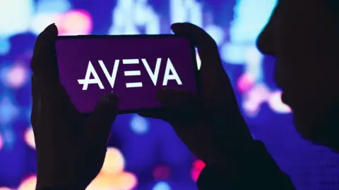 SOPA Images/Getty Images Woman hols phone with Aveva logo