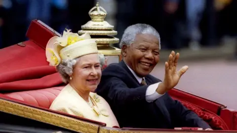 Reuters Nelson Mandela waves to a crowd while riding in a royal carriage alongside Queen Elizabeth II