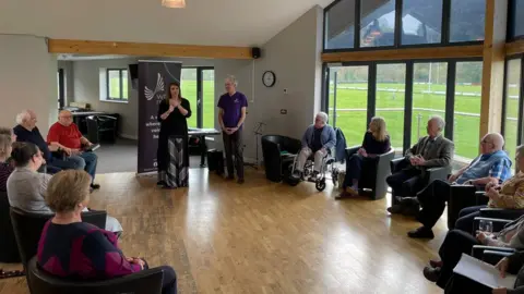 Wren Music People sitting at a singing group in a hall