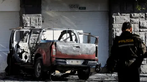 Reuters A police officer stands near the remains of a car in Quito, Ecuador