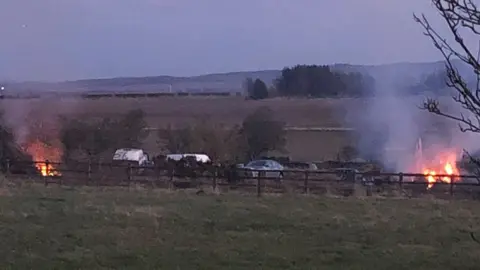 Environment Agency Cars in a field with fires around them