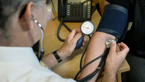 PA Media A GP checking a patient's blood pressure