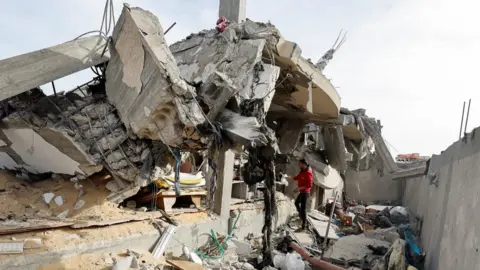 Reuters A Palestinian man inspects a building destroyed in a reported Israeli air strike in Rafah, in the southern Gaza Strip (26 March 2024)