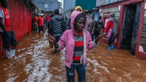 Getty Images Residents are seen in a flooded street of Mathare neighborhood after heavy rains as they try to evacuate the area with their important belongings in Nairobi, Kenya on April 24, 2024