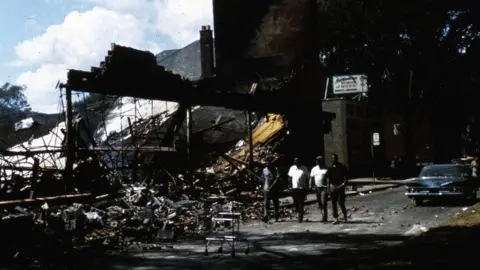 David Marchioni Four unidentified African American men walk past the rubble of a storefront in Detroit 1967.