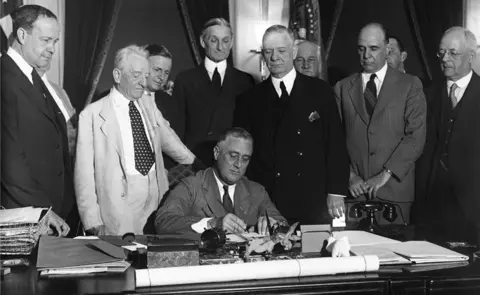 Alamy  Franklin Roosevelt signs the Glass-Steagall banking reform act on 16 June, 1933.