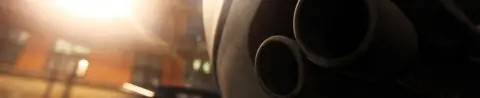 Getty Images An exhaust pipe sticks out the rear of a car parked on a street