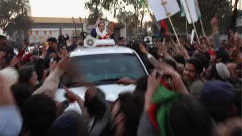 Getty Images Former Prime Minister Benazir Bhutto waves from her car just seconds before being attacked on December 27, 2007 in Rawalpindi, Pakistan.