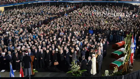 AFP/Getty Images  Hassan Guillet delivers the eulogy at the funeral for Abdelkrim Hassane, Khaled Belkacemi and Aboubaker Thabti